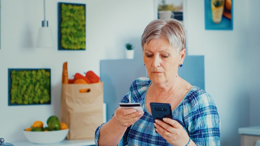 Senior woman paying online using phone